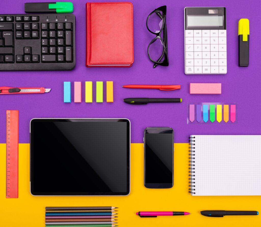 Modern working place with tablet, calculator, notebook and smartphone on purple and orange